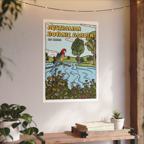 Poster placed on a wall of a cartoon of the Australian Botanic Garden in Mt Annan. Featuring a black outlined rosella sitting on a branch, with the background of a flowing lake and trees in the hills. Pink, yellow and white wildflowers frame the bottom.